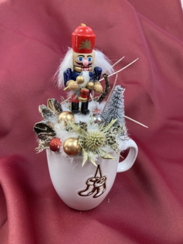 Diótörő Domán ezüst fenyőfával és iringóval ékített karácsonyi töltött bögrécskéje tartós virágdísz