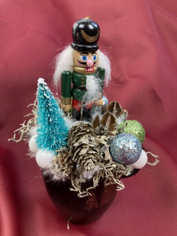 Diótörő Donát türkiz fenyőfával és zuzmóval ékített karácsonyi töltött bögrécskéje tartós virágdísz