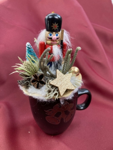 Diótörő Dorián türkiz fenyőfával, iringóval és brunniával ékített karácsonyi töltött bögrécskéje tartós virágdísz