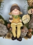 Kép 2/4 - Őszi, dértől csillogó ruhás, makkos sapkás, láblógató kislány természetes összetevőjű terméskopogtatója