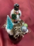 Kép 1/4 - Diótörő Donát türkiz fenyőfával és zuzmóval ékített karácsonyi töltött bögrécskéje tartós virágdísz