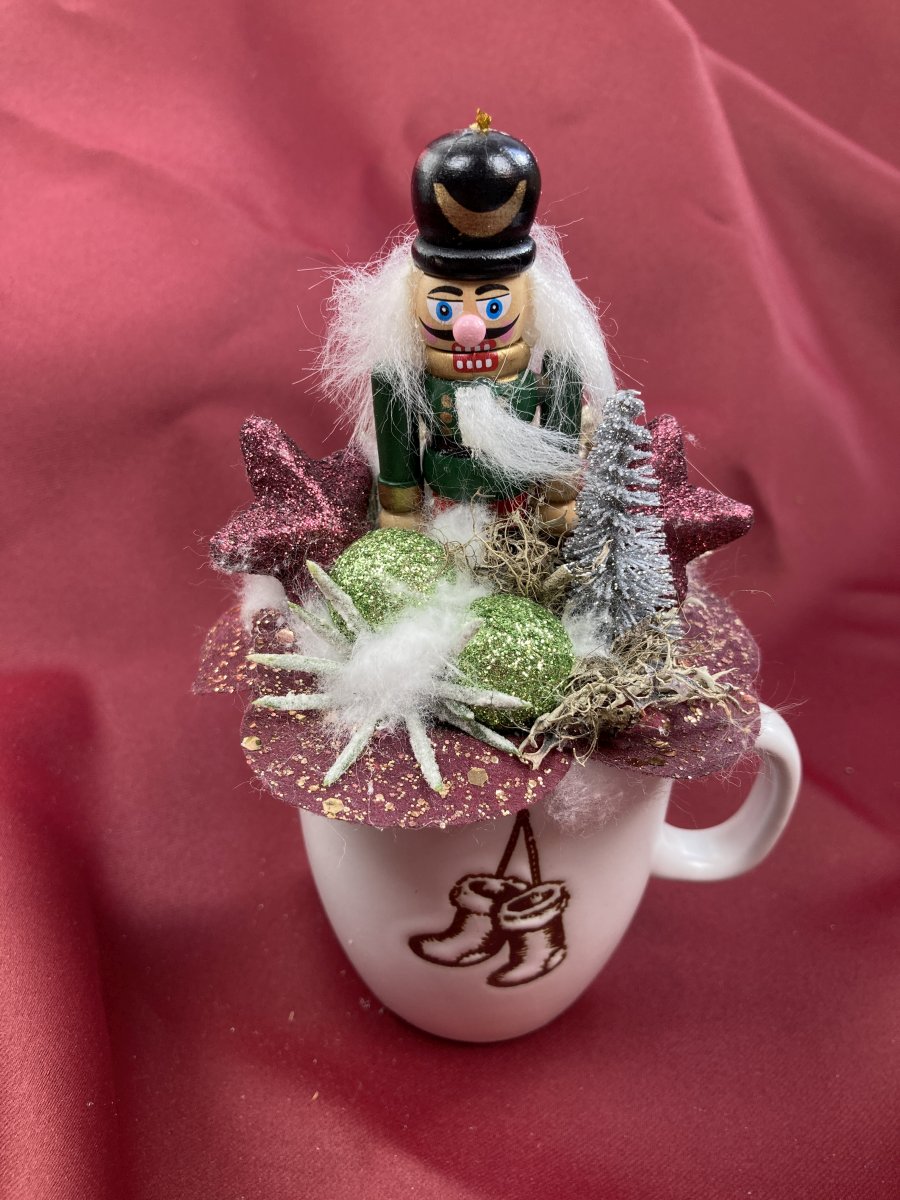 Diótörő Donald bordó levelekkel és ezüst fenyőfával ékített karácsonyi töltött bögrécskéje tartós virágdísz