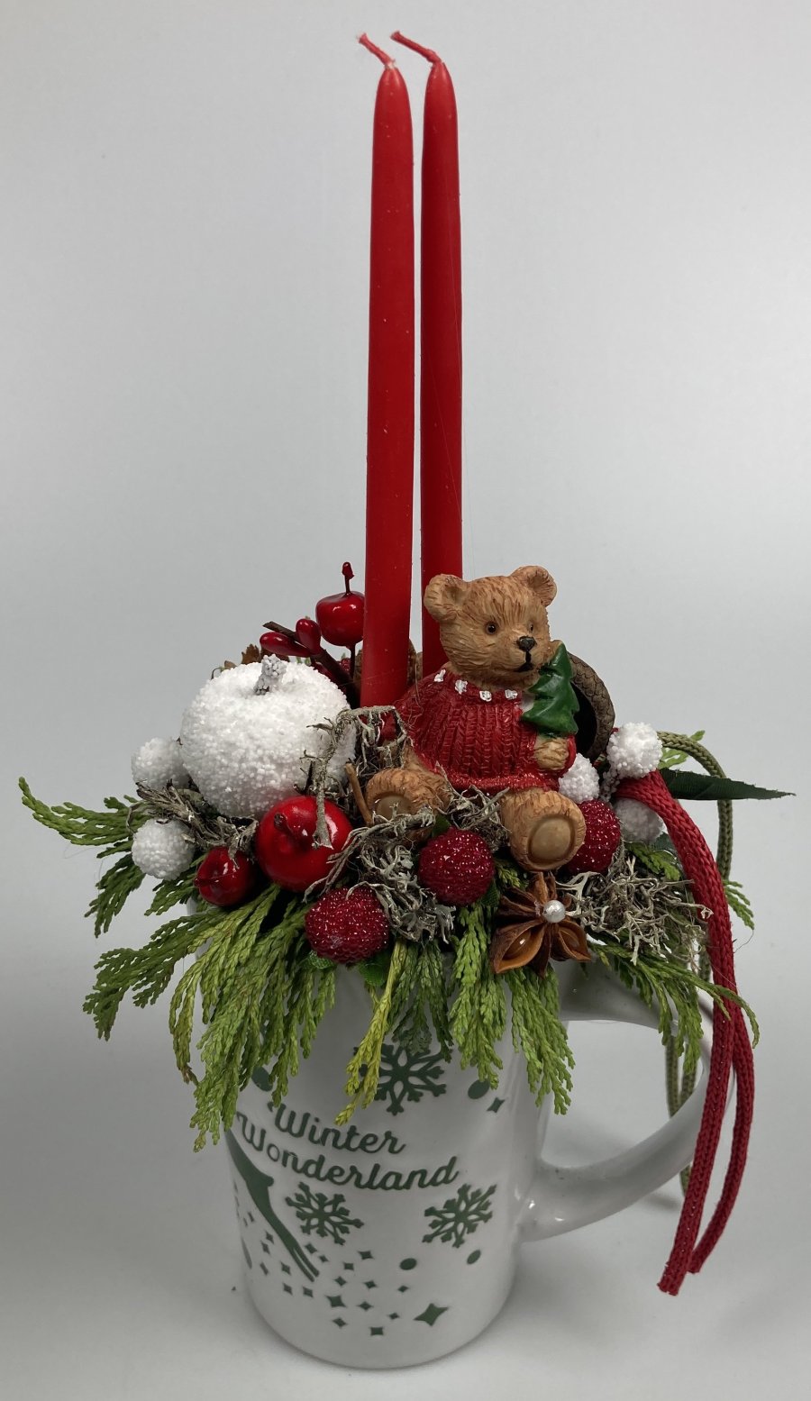 Piros pulcsis, szedresben csücsülő maci, töltött karácsonyi kerámiabögre tujaágyon, szalagokkal